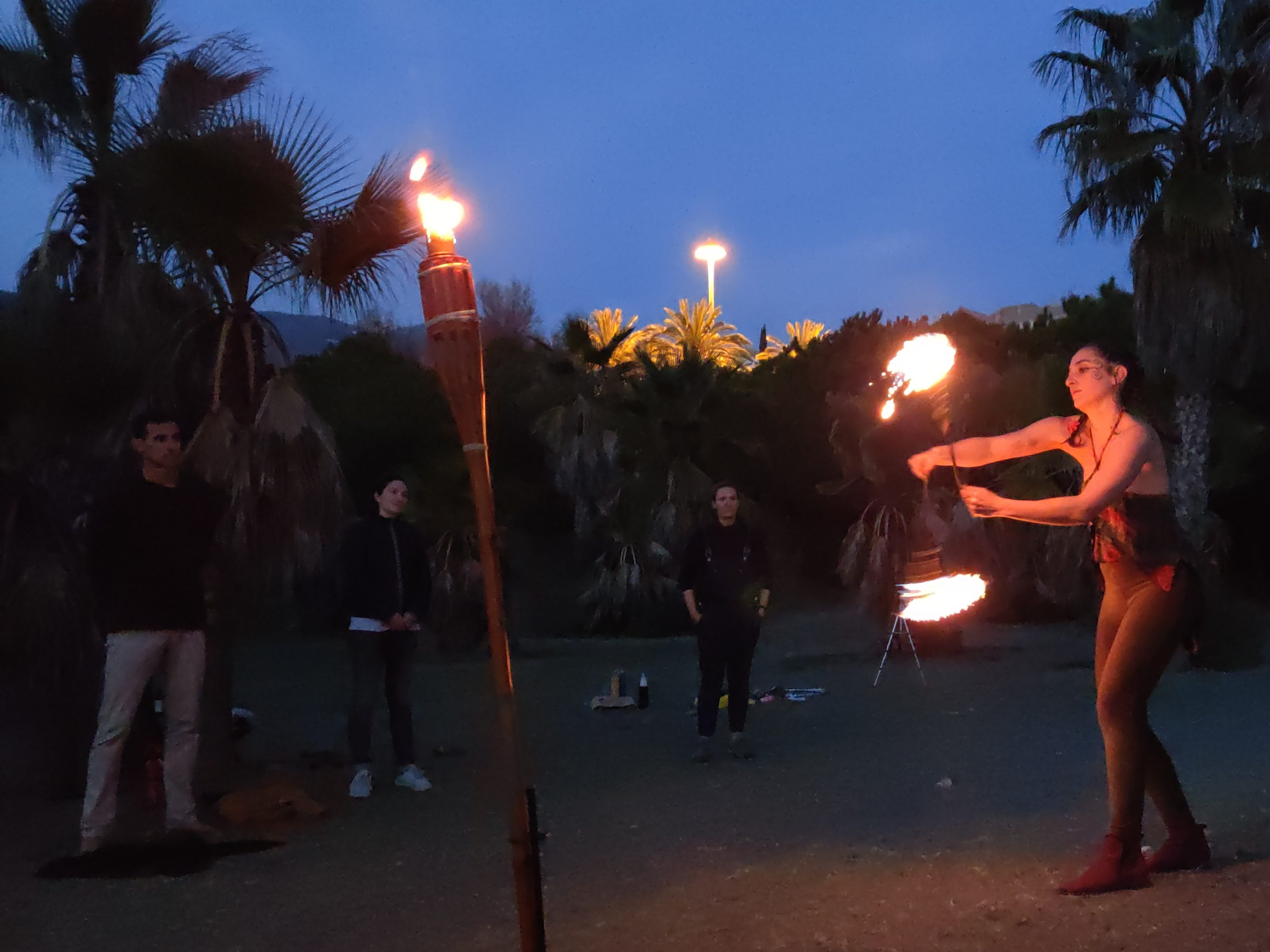 Maka bailando con cariocas de fuego en la demostración de habilidades al final de su clase de baile con fuego. Vito junto a las personas que realizaron la clase con ella disfrutan del show