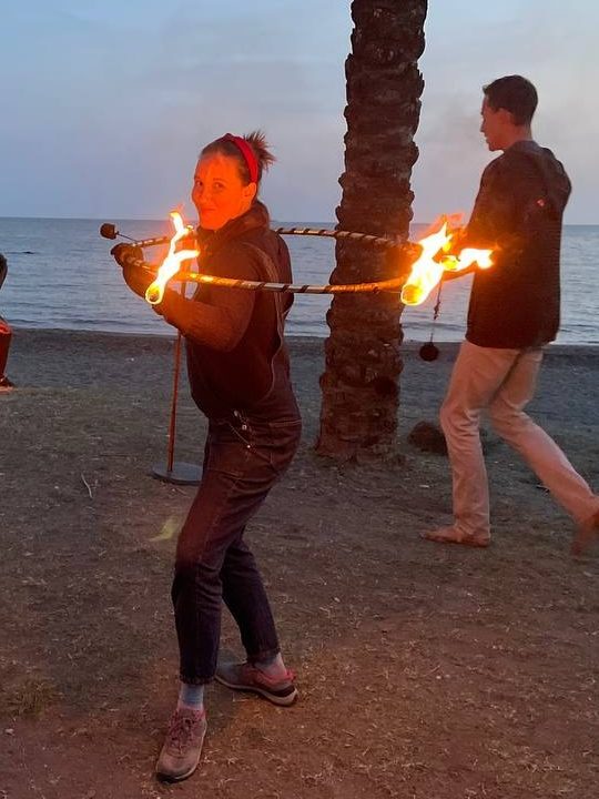 Victoria en su primera clase de baile con fuego bailando con el hula hoop de fuego. Su cara es sonriente y feliz